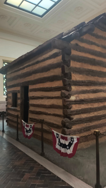 A reconstructed one-room log cabin representing Abraham Lincoln’s birthplace sits within the neoclassical memorial at the site. (credit: Mark Gresham, March 31, 2026)