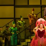 Angela Meade (front right) as Princess Turandot. Behind her, on the top step, Jonathan Burton, wearing a leather jacket, as Prince Calaf, and Steven Cole, in purple robes, as Emperor Altoum. (credit: Raftermen)